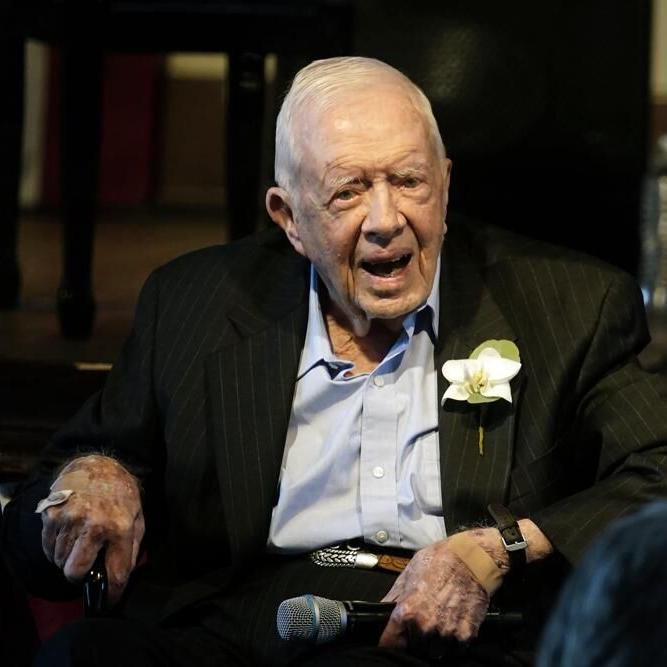 Former President Jimmy Carter reacts as his wife Rosalynn Carter speaks during a reception.jpeg